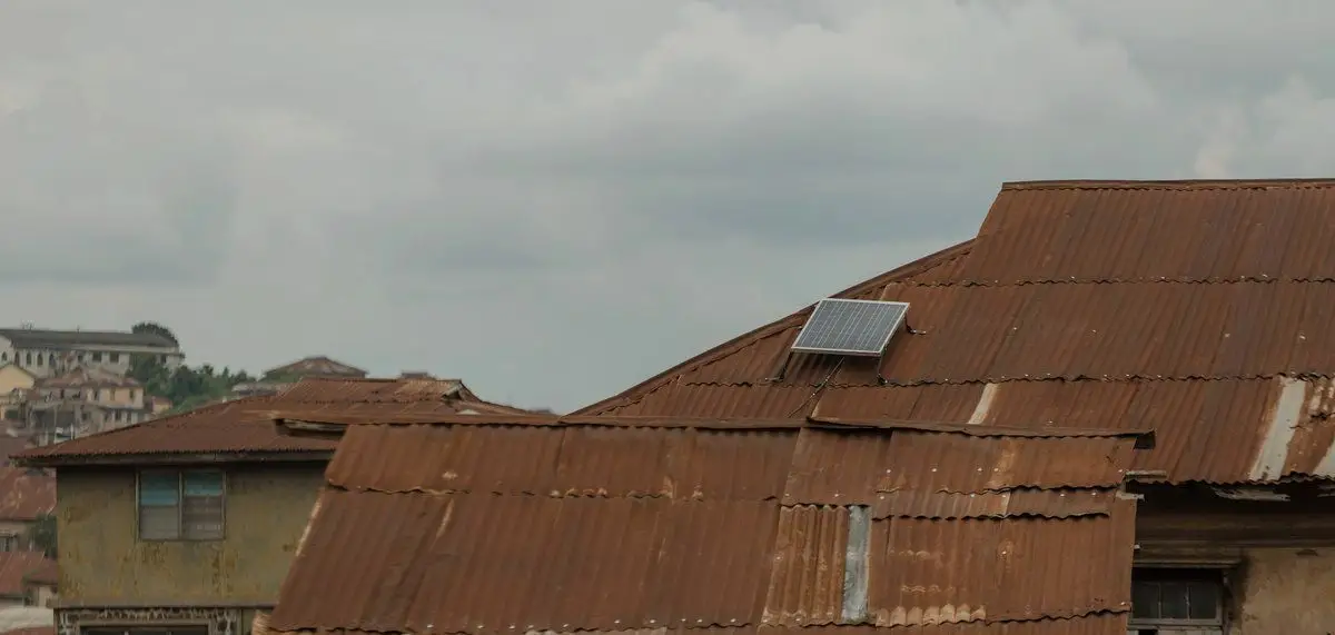 Solar panel on the corrugated roof of an old house in Abeokuta, Ogun State, among dense rooftops
