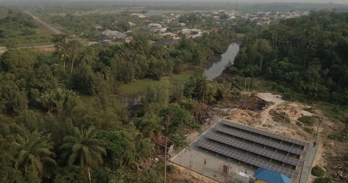 Aerial view of a solar mini-grid array beside a river and forest in Bayelsa State, Nigeria